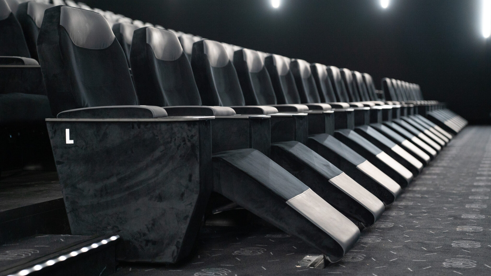 Rangée de fauteuils inclinables haut de gamme dans une salle de cinéma CGR